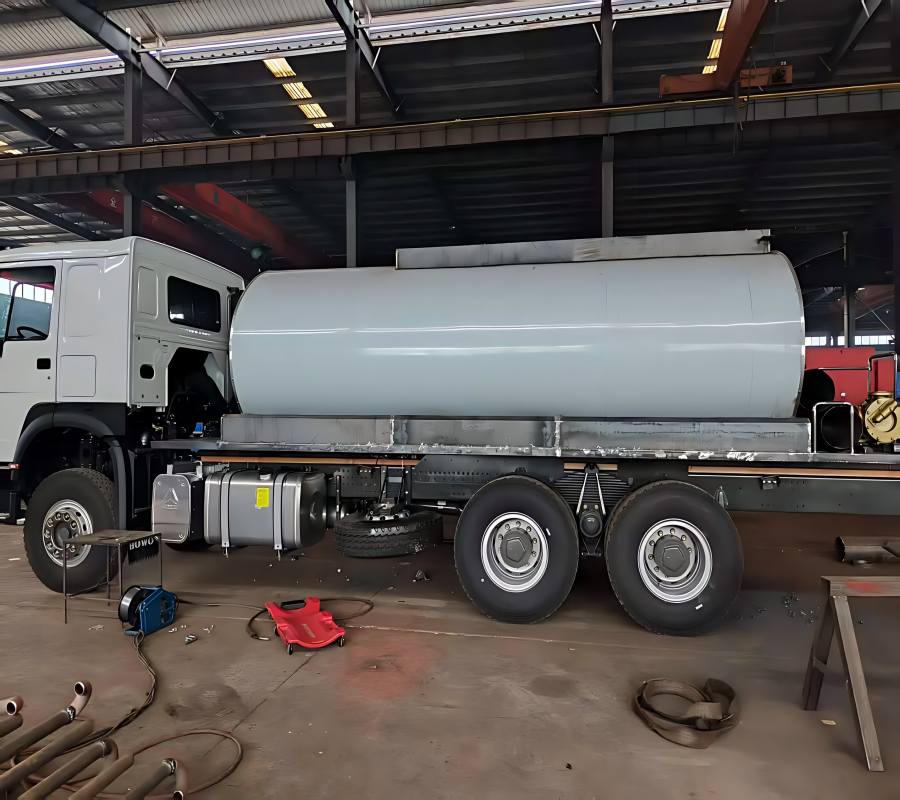 A wide-angle view of the SINOTO asphalt distributor factory floor with multiple truck-mounted sprayers during the assembly process.